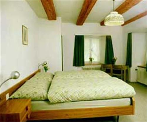 a bed in a bedroom with green curtains at Landgasthof St. Luzisteig in Maienfeld