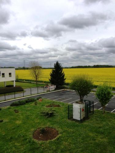 an empty parking lot with a field of yellow rapeseed at ibis budget Santeny in Santeny