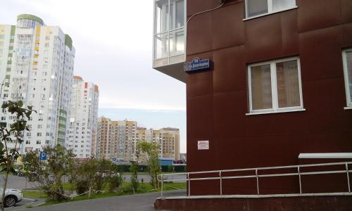 チュメニにあるКвартира-студия рядом с ТРЦ Кристалл-Леруа Мерленの高層ビルの隣の赤い建物