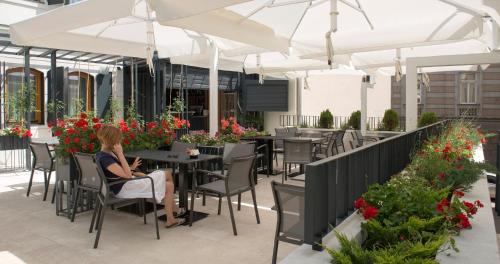 a patio area with chairs, tables and umbrellas at Hotel Sana in Sarajevo