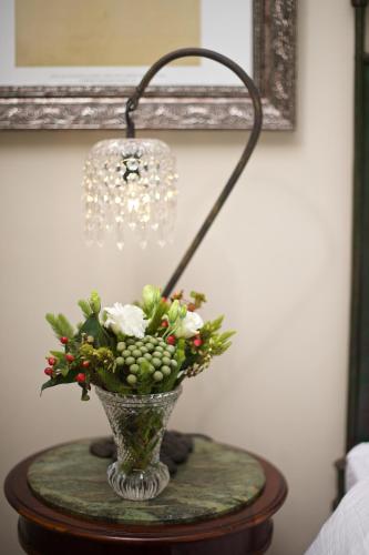 a lamp on a table with a vase with flowers at Baruch Guesthouse on Lovell in Stellenbosch
