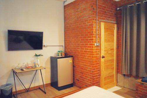 a room with a refrigerator and a brick wall at Indiego Space in Loei
