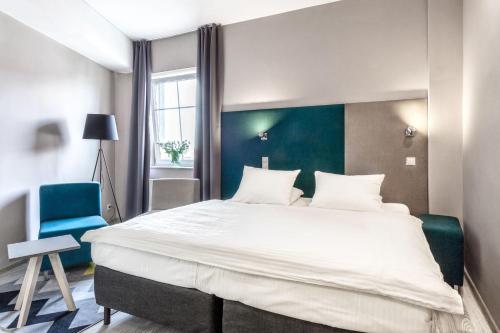 a bedroom with a large bed and a blue chair at Hotel Kaliski in Słubice