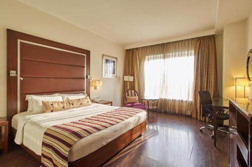 a hotel room with a large bed and a window at Royal Orchid Central, Pune in Pune