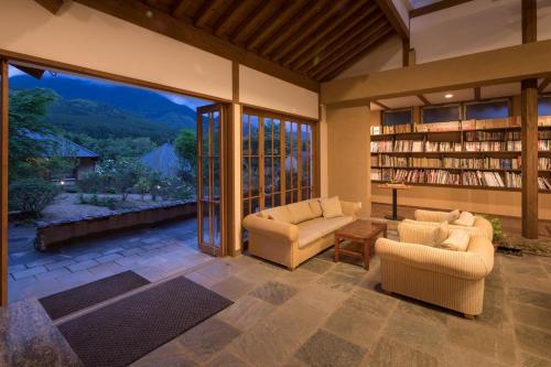 una sala de estar con 2 sofás y un estante para libros. en Ikkoten en Yufuin