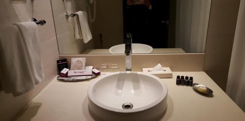 a bathroom with a white sink and a mirror at Royal Orchid Central, Pune in Pune