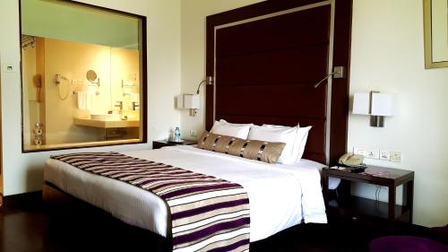a hotel room with a large bed and a bathroom at Royal Orchid Central, Pune in Pune