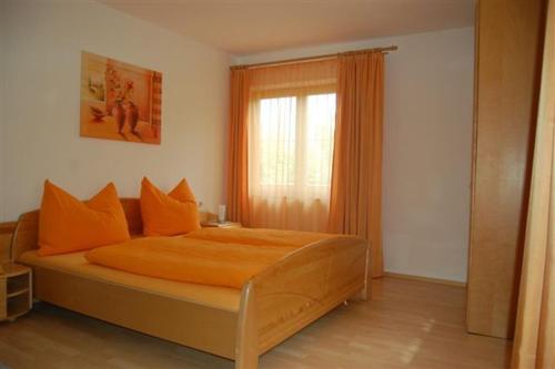 ミーダースにあるHaus Gantiolerのベッドルーム1室(オレンジ色の枕と窓付)