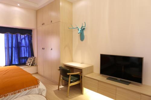a bedroom with a bed and a flat screen tv at Yumi Apartment Lida Plaza Branch in Guangzhou
