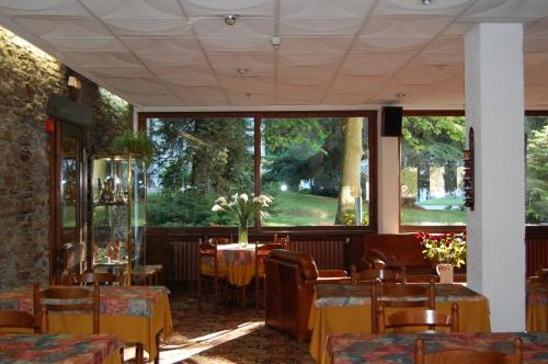 un restaurante con mesas y sillas y una gran ventana en Hôtel de Paris, en Luchon