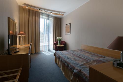 a hotel room with a bed and a desk at Perkuno Namai Park Hotel in Kaunas