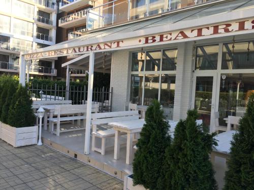 a restaurant with white benches in front of a building at Beatris Family House in Sunny Beach