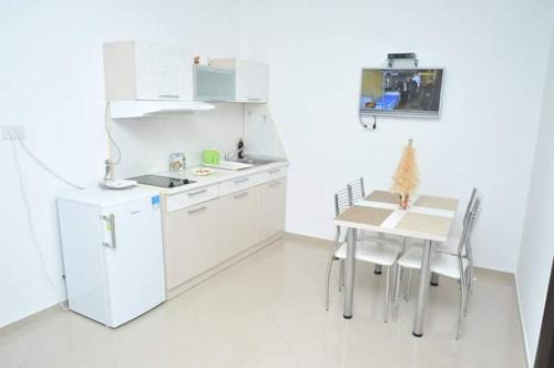 a white kitchen with a table and a table and chairs at Apartmani "ROSHU" in Soko Banja