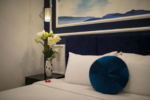 a bed with a blue pillow and a vase of flowers at Hanoi Chic Boutique Hotel in Hanoi