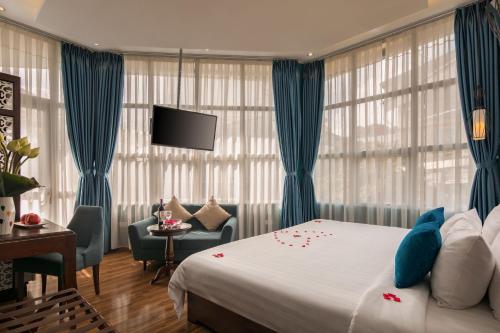 a hotel room with a bed and a chair and a television at Hanoi Chic Boutique Hotel in Hanoi