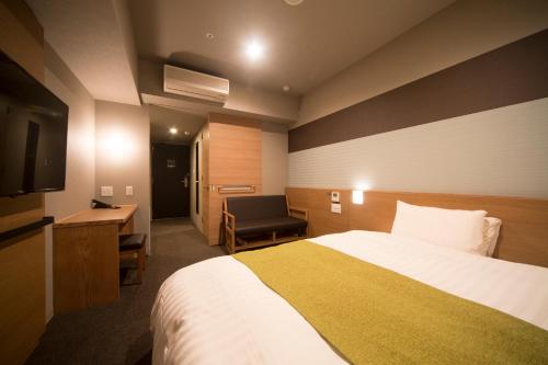 a hotel room with a bed and a desk and a television at Dormy Inn Izumo in Izumo