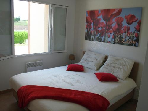 une chambre avec un lit avec deux oreillers rouges dans l'établissement Poolside Apartment in Segonzac, à Segonzac