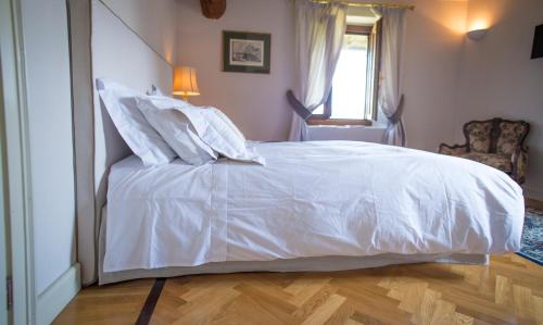 a white bed in a bedroom with a wooden floor at Castello Di Mornico Losana in Mornico Losana