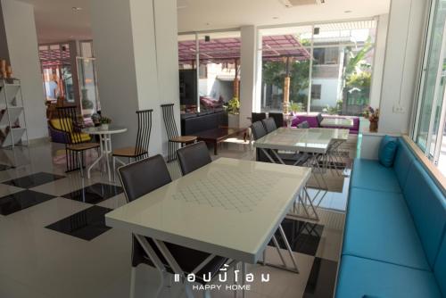 Un comedor con mesas y sillas y ventanas. en Happy Home, en Ratchaburi