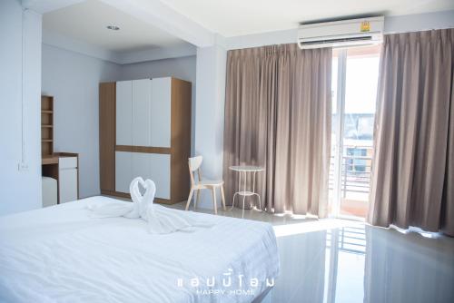 a bedroom with a white bed and a large window at Happy Home in Ratchaburi