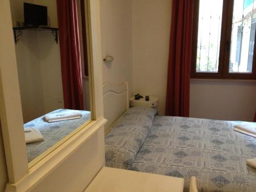 a small bedroom with a bed and a mirror at Albergo Sonia in Florence