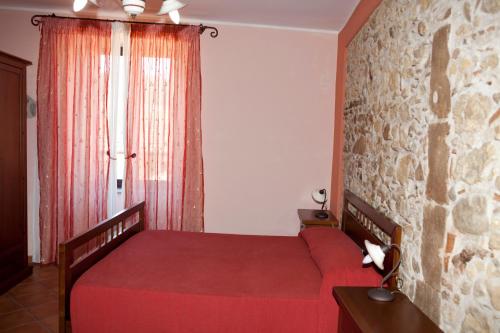 a bedroom with a red bed and a window at B&B Del Borgo in San Marco Argentano