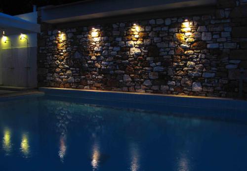 a stone wall with lights next to a swimming pool at Thalassa in Loutra Edipsou