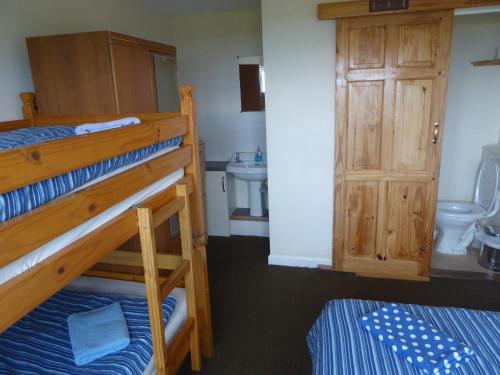 a bedroom with two bunk beds and a bathroom at Longbeach- Adults Only in Newquay