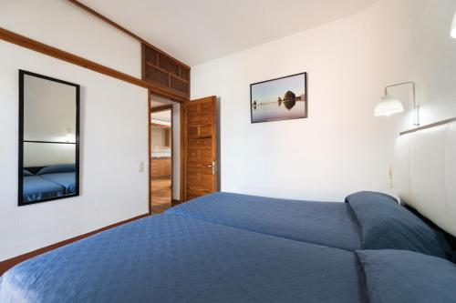 a bedroom with a blue bed and a mirror at Apartamentos Don Pedro in Playa del Ingles