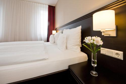 a hotel room with a bed with a vase of flowers on a table at Göbel's Sophien Hotel in Eisenach