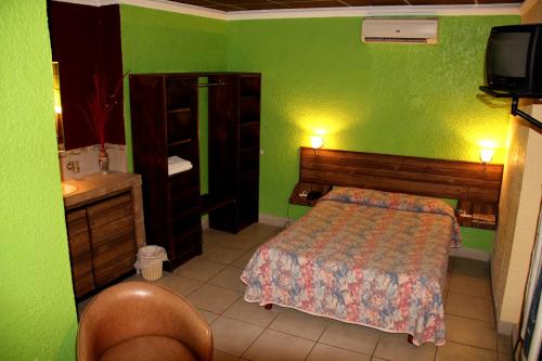 Dormitorio verde con cama y TV en Hotel Miramar - La Paz, en La Paz