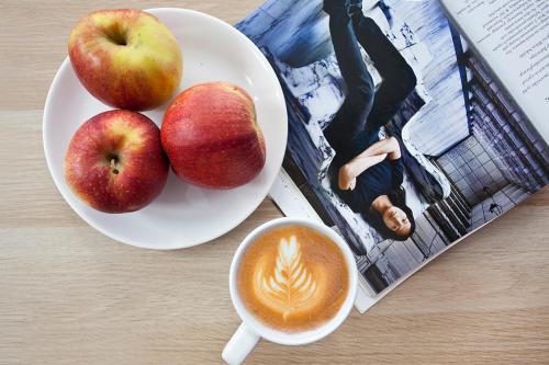 dos manzanas y una taza de café y una revista en Aparts Sopot en Sopot