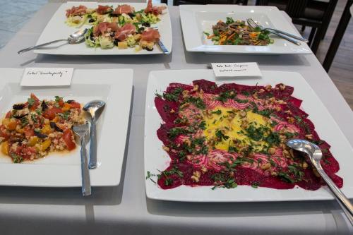 three plates of food on a table with spoons at Historik Hotel Garni Christinenhof in Hameln