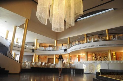 a woman walking through a shopping mall with a chandelier at Hotel Magic GT Trivale in Piteşti