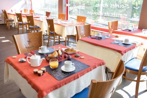 uma sala de jantar com duas mesas com comida em Hôtel Les Gens De Mer Lorient by Popinns em Lorient