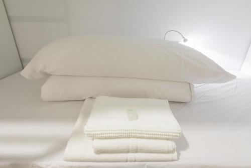 a pile of white towels sitting on a bed at Globetrotter Hostel in León