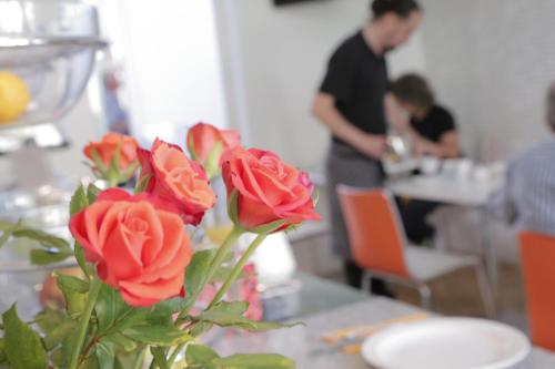 Un vase de fleurs sur une table, avec un homme en arrière-plan. dans l'établissement B&B Belgravia, à Londres
