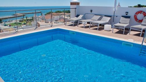 a swimming pool with chairs and a view of the ocean at Topcity Hostel & Suites in Lagos