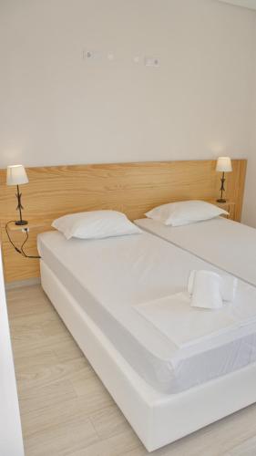 a large white bed with two pillows and two lamps at Topcity Hostel & Suites in Lagos