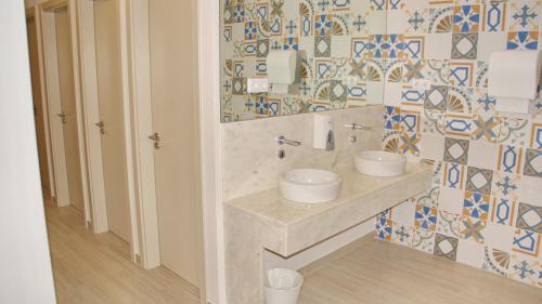 a bathroom with two sinks and a tiled wall at Topcity Hostel & Suites in Lagos