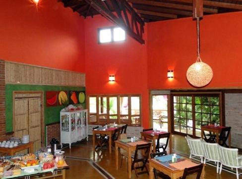 un restaurante con paredes rojas, mesas de madera y sillas en VELINN Pousada Catamarã Brasil, en Ilhabela