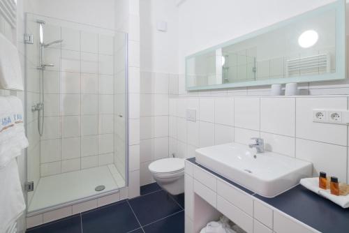 a white bathroom with a sink and a toilet at Taba Hotel in Kellinghusen