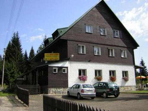 ein großes Haus mit zwei Autos davor geparkt in der Unterkunft Horsky hotel Sport in Josefův Důl u Jablonce nad Nisou