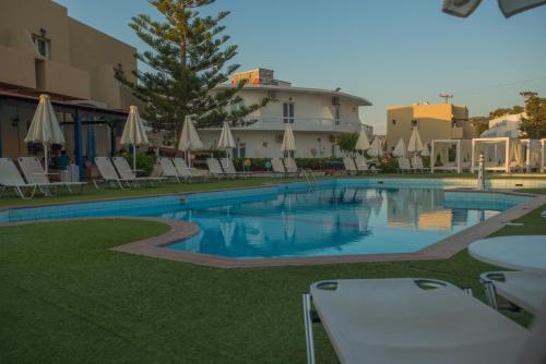 une grande piscine avec des chaises et un bâtiment dans l'établissement Fragiskos Hotel, à Matala