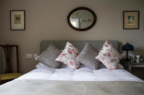 a bedroom with a bed with pillows and a mirror at Pennygate Lodge in Craignure