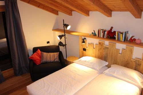 een slaapkamer met een bed en een stoel bij Le jardin de Pierre in Nus