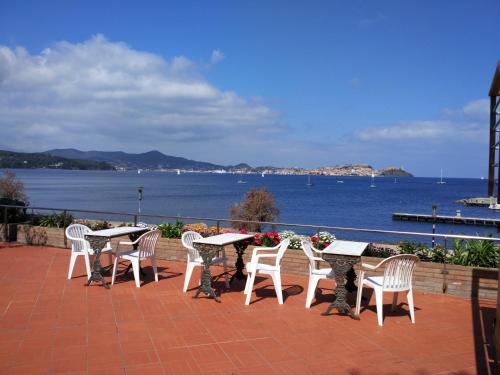 a group of tables and chairs on a patio overlooking the water at Hotel Mare in Portoferraio