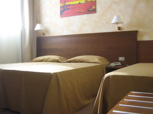 a hotel room with two beds and a headboard at Hostiliae Ciminiera Hotel in Ostiglia