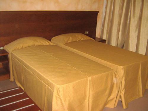 a bed with a yellow cover on top of it at Hostiliae Ciminiera Hotel in Ostiglia
