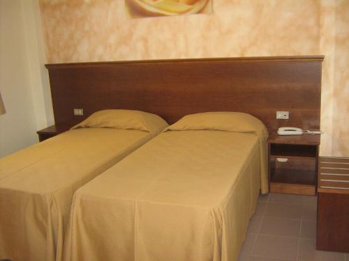 a bedroom with two beds and a wooden headboard at Hostiliae Ciminiera Hotel in Ostiglia